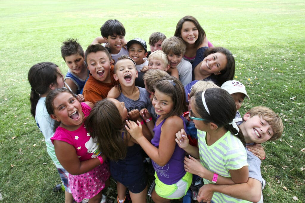 Diverse group of children in a happy huddle at a Denver park.