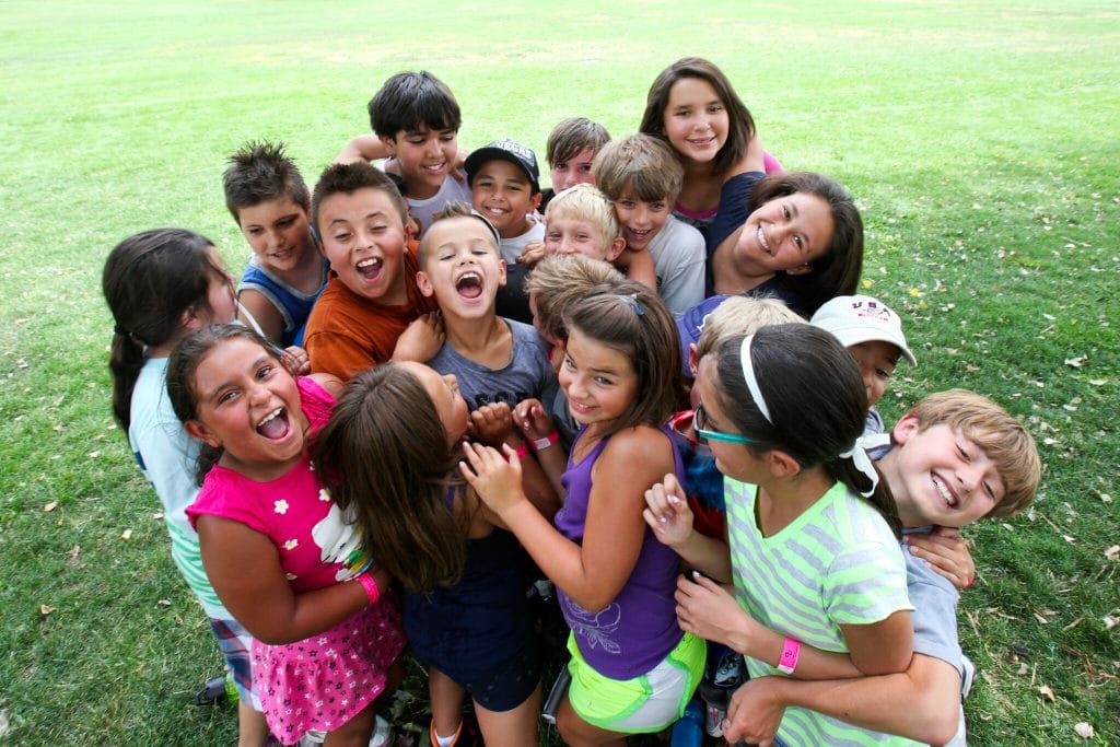 Diverse group of children in a happy huddle at a Denver park.
